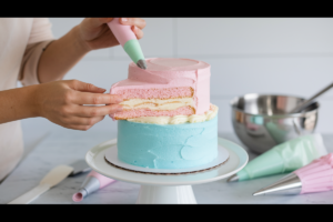 Baker assembling a pastel cotton candy cake with frosting.