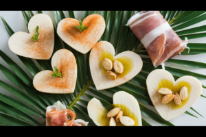 A flat lay of quick snack ideas with hearts of palm, featuring slices with smoked paprika, prosciutto wraps, and a garlic olive oil toss