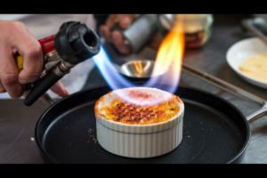 Blowtorch caramelizing sugar on crab brûlée.